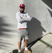 a man wearing a hat and shorts standing in front of a wall